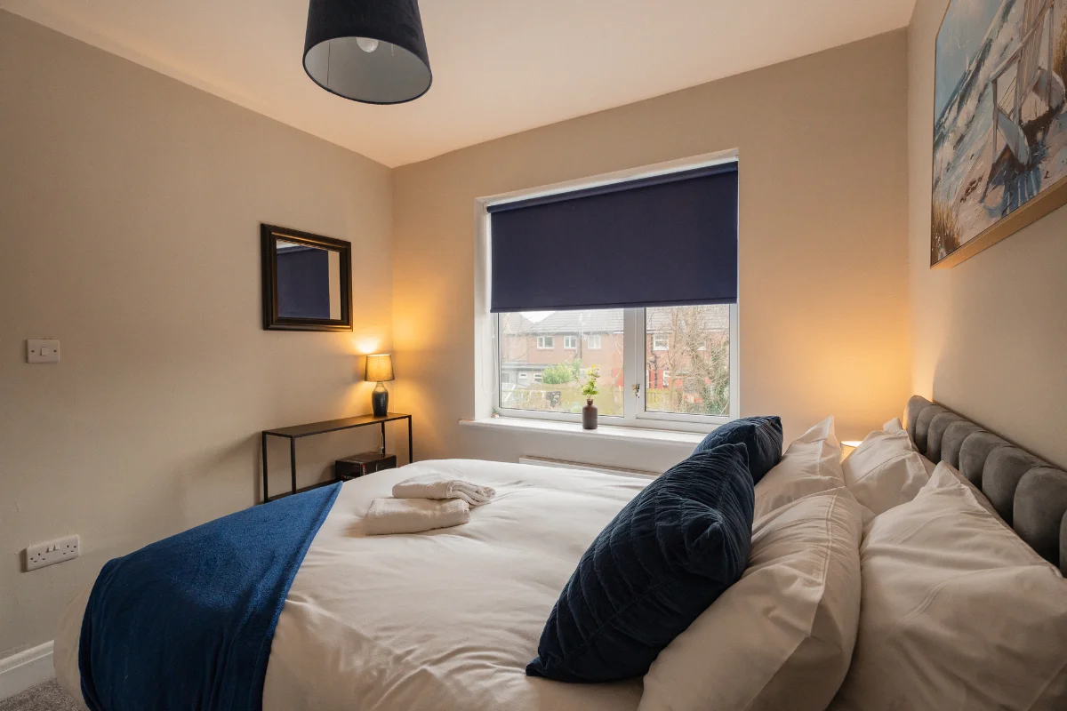 Cosy holiday cottage bedroom with double bed, blue accents and window blind
