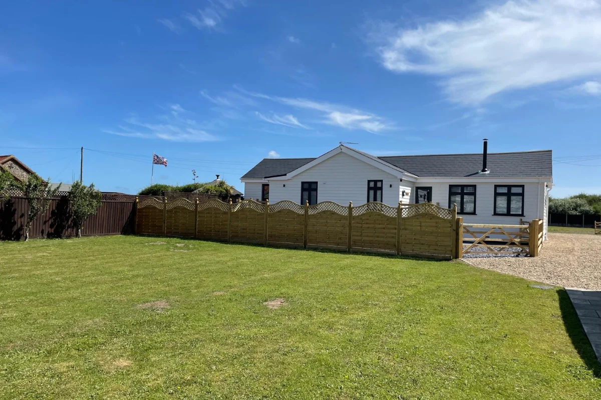 White countryside holiday lodge with fenced garden, lawn and gravel driveway