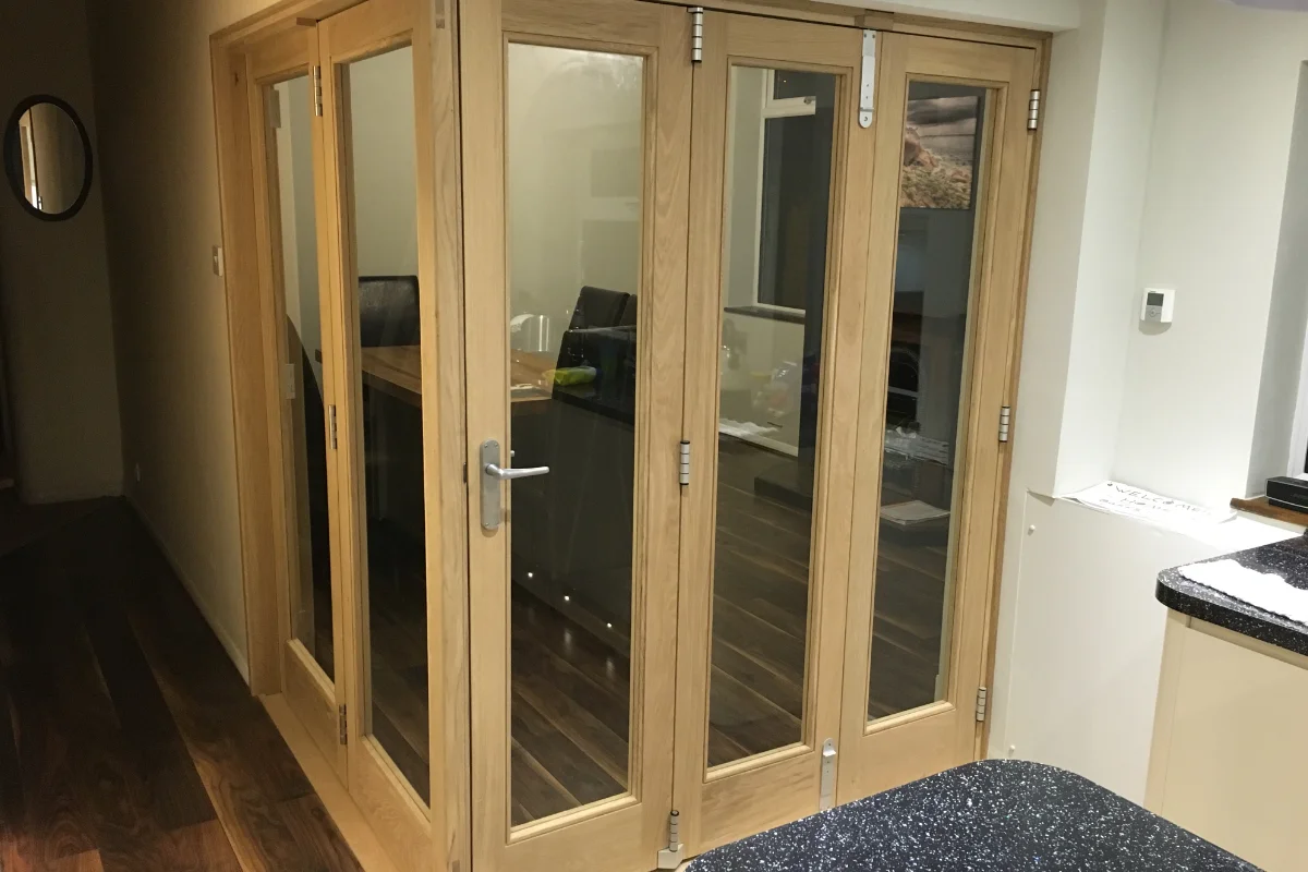 Interior wooden bi-fold doors with glass panels, oak frame, and silver handles