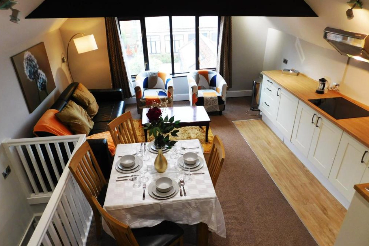 Open plan holiday cottage kitchen, dining and living area with table set for four